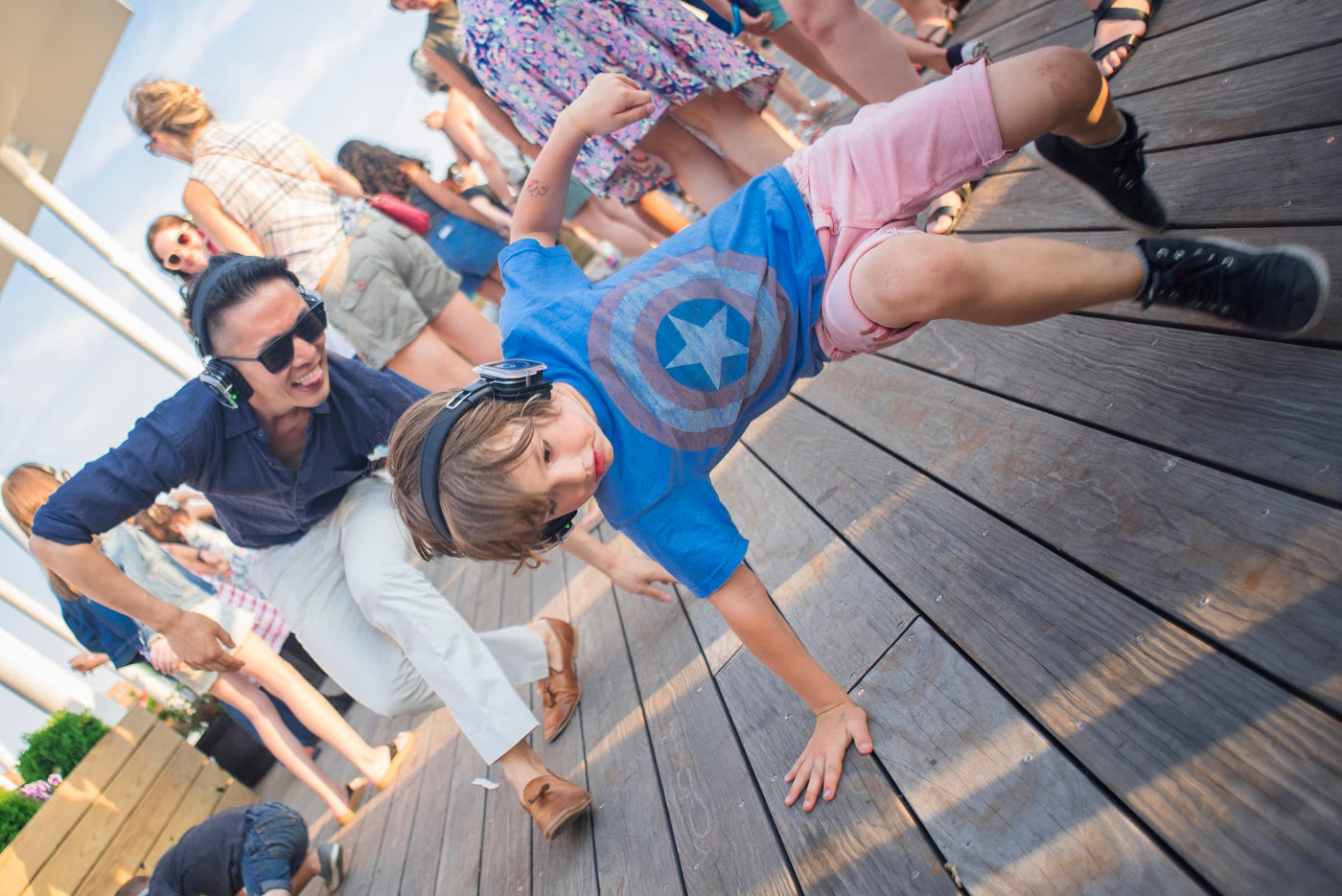 Quiet Events Silent Disco headphones for bar mitzvah. A young boy breakdancing in front of group of adults.