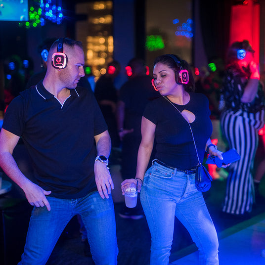 Quiet Events Silent Disco headphones for corporate party. A couple on the dance floor having fun with headphones.