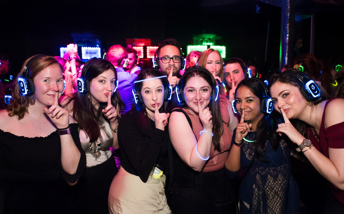 Quiet Events Silent Disco headphones for dance parties a group posing with headphones and indicating to be silent with their fingers.