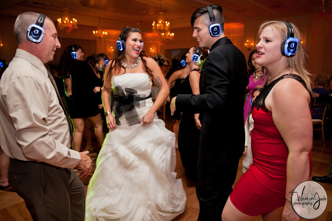 Quiet Events Silent Disco headphones for weddings. A happy newly wed couple dancing on the floor with others wearing headphones.