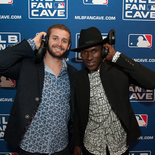 Quiet Events Silent Disco headphones for sporting events. two gentleman posing for a picture with headphones with a MLB background.