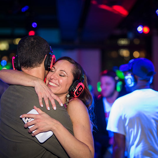 Quiet Events Silent Disco headphones for a wedding. A couple dancing, hugging and happy together wearing headphones.