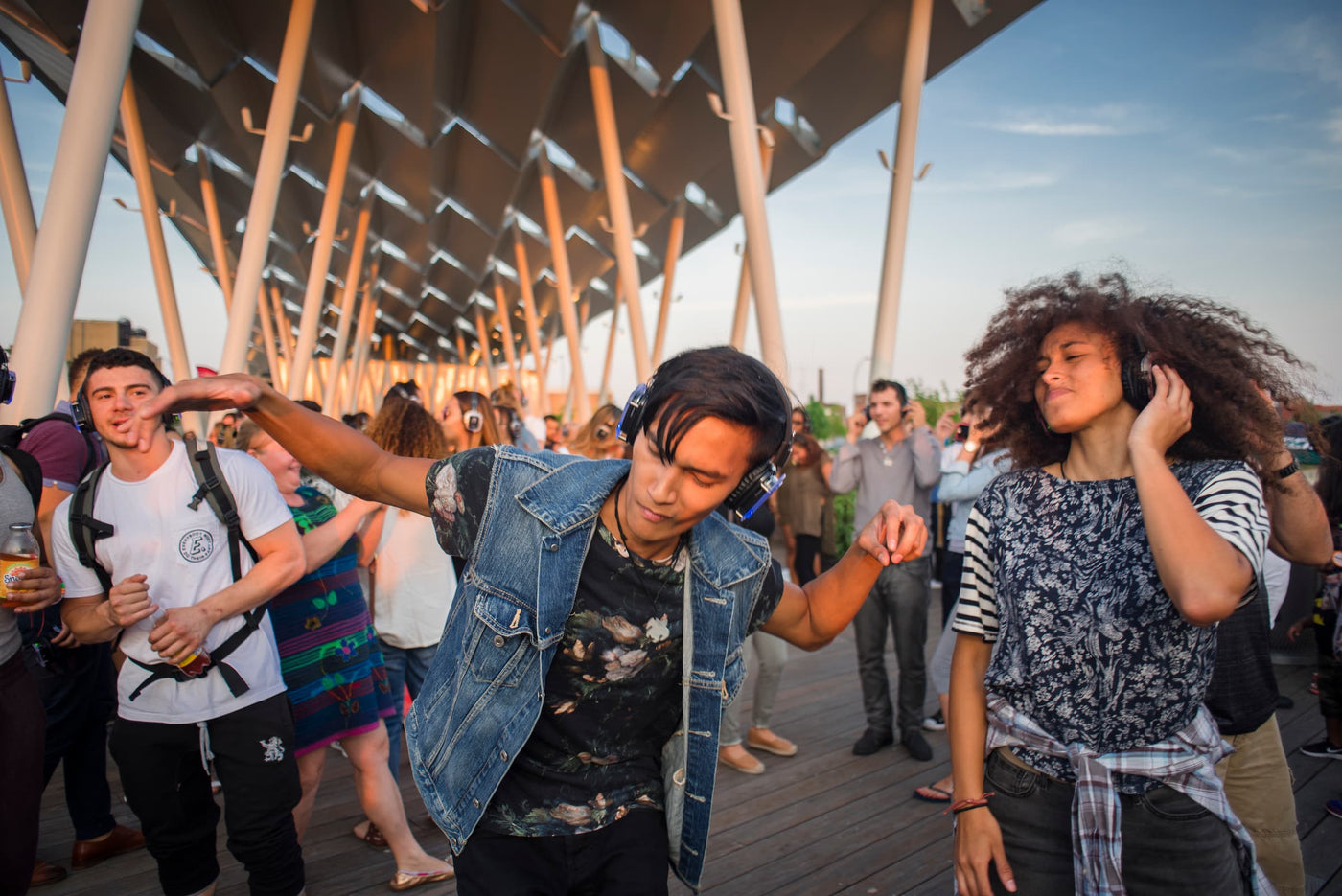 Quiet Events Silent Disco headphones for Property Management. A group of young adults dancing and having fun outdoors with headphones.