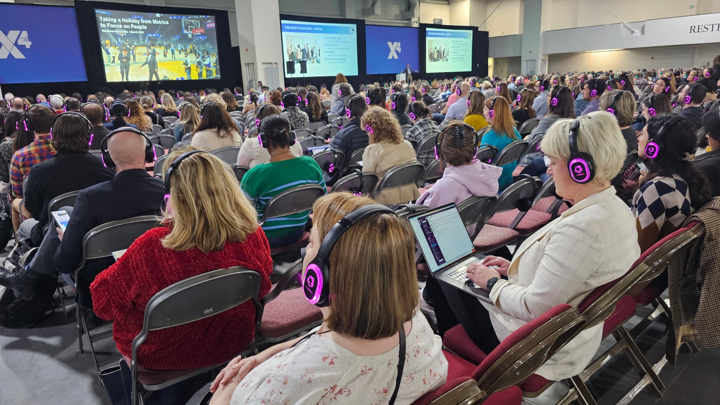 Quiet Events Silent Disco headphones for  Conferences with a group of people looking at a screen with headphones on.