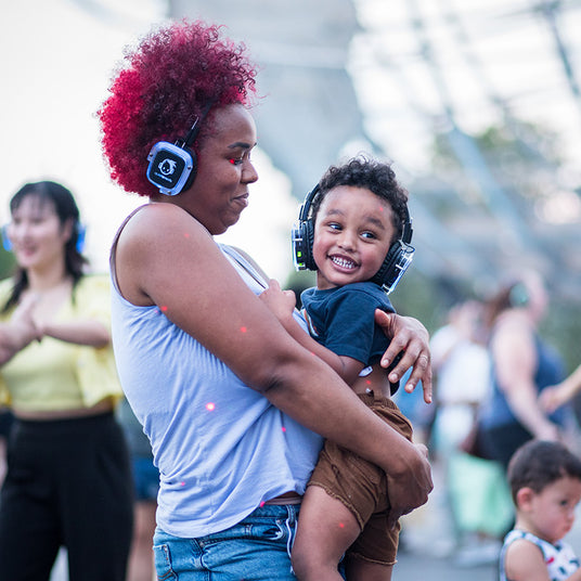 Quiet Events Silent Disco headphones for all ages; a mother and baby son  held together enjoying and having fun with headphones.