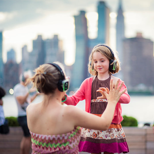 Quiet Events Silent Disco headphones for all ages.  A mother and daughter having fun outdoors with headphones.