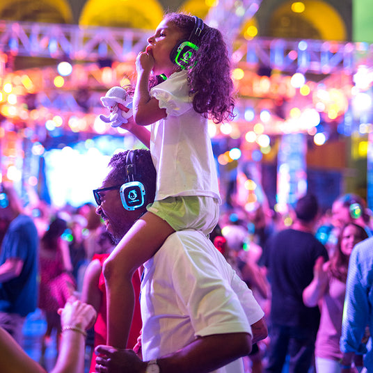 Quiet Events Silent Disco headphones for all ages.  A father with her daughter on his shoulders at a festival having fun.