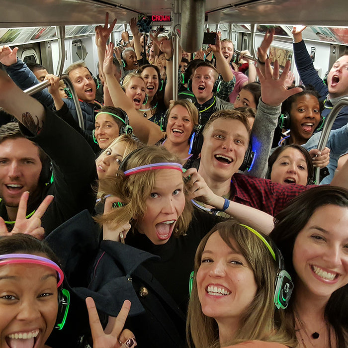 Quiet Events Silent Disco headphones for all ages.  A group of people on a subway car having fun listening with headphones.