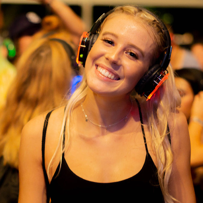 Quiet Events Silent Disco headphones for assistive listening.  A girl is up close having fun and smiling wearing headphones with others in the background.