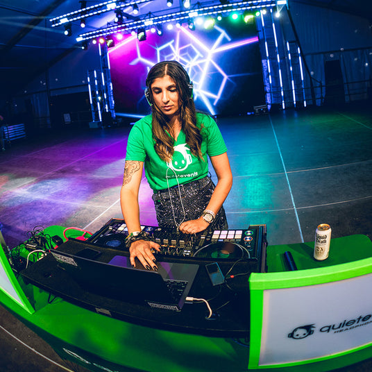 Quiet Events Silent Disco headphones for bachelorette.  A female DJ mixing on a stage wearing wearing headphones.