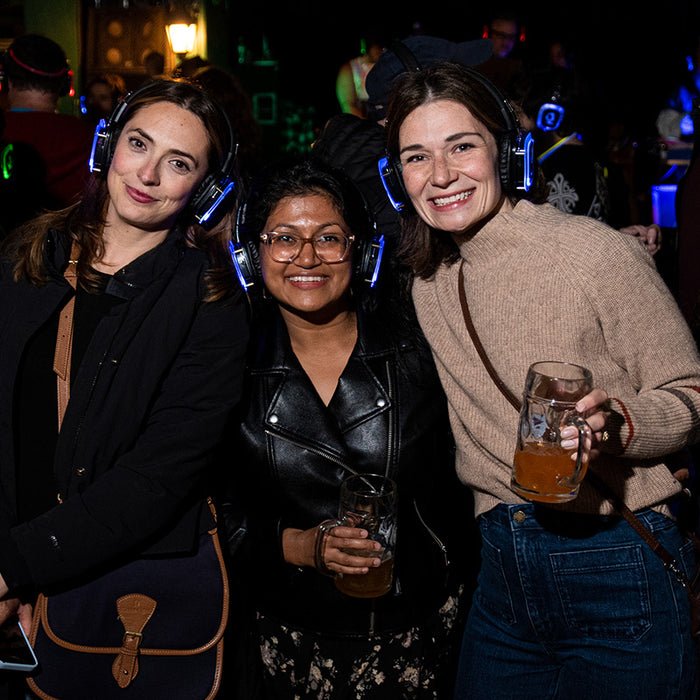 Quiet Events Silent Disco headphones for beer garden event. Three girls having fun enjoying their company listening to music with headphones.