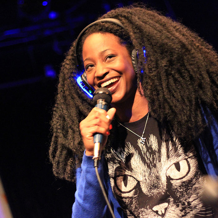 Quiet Events Silent Disco headphones for comedy.  An african american woman on stage speaking on a mic with headphones.