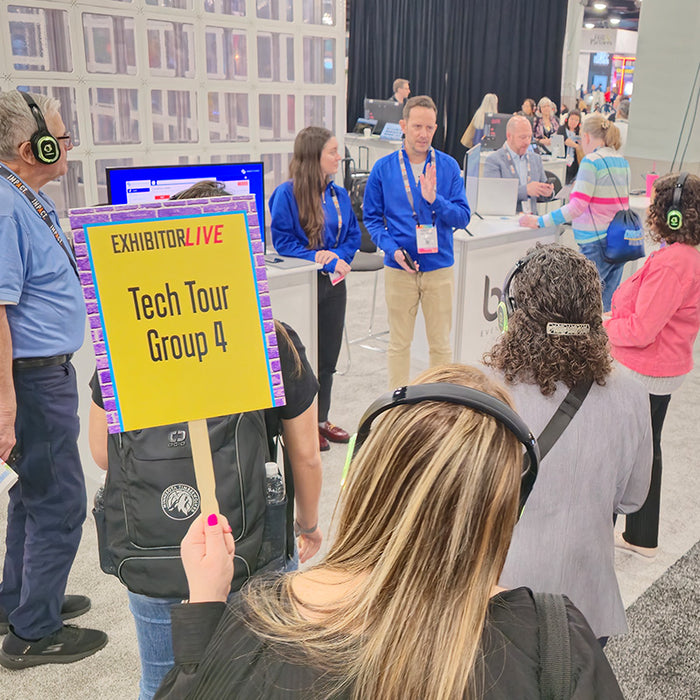 Quiet Events Silent Disco headphones for convention at expo a group of people wearing headphones listening to a speaker at a booth.