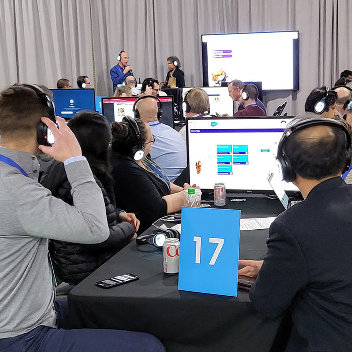 Quiet Events Silent Disco headphones for conventions training a group of people sitting with screens paying attention to an instructor 
