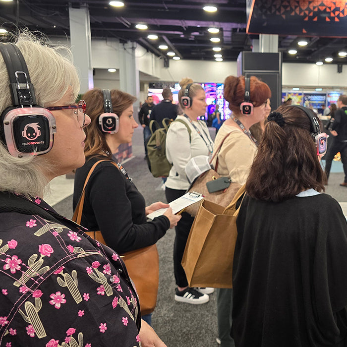 Quiet Events Silent Disco headphones for convention a group of people standing and listening with headphones  on the expo floor