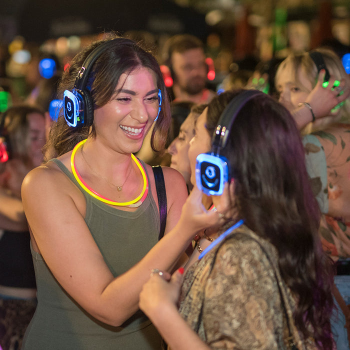 Quiet Events Silent Disco headphones for dance parties two girls having fun and adjusting their volume.