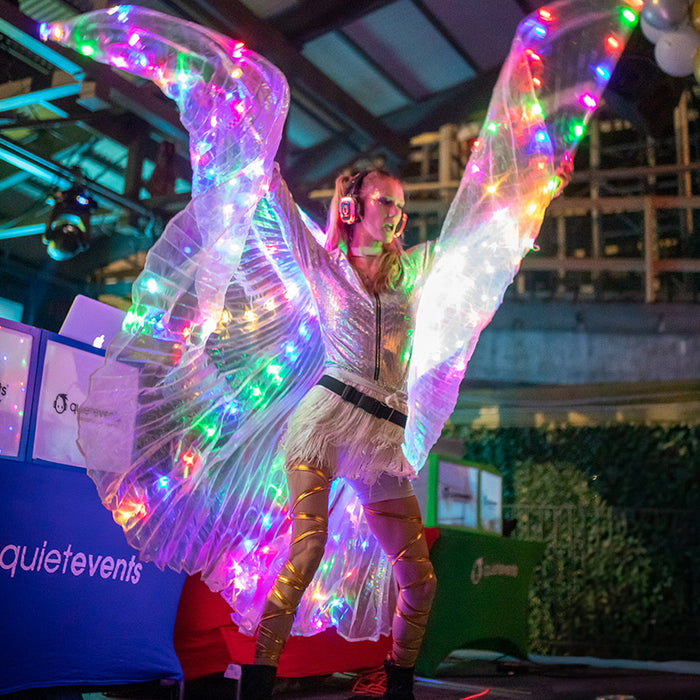 Quiet Events Silent Disco headphones for fashion shows. A girl on stage entertaining with a butterfly custom and wearing headphones.