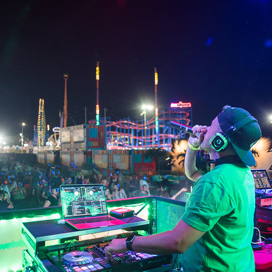 Quiet Events Silent Disco headphones for festivals a DJ holding a mic on stage   at an amusement park