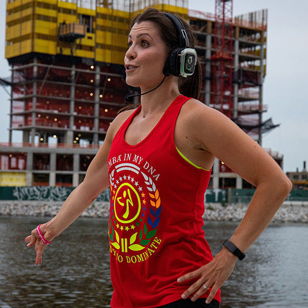 Quiet Events Silent Disco headphones for health and wellness.  A instructor wearing headphones talking over a microphone to her students outdoors.