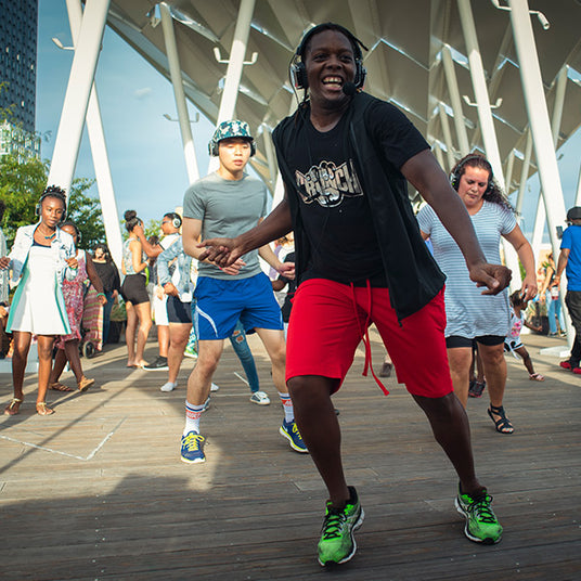 Quiet Events Silent Disco headphones for health and wellness.  An instructor having fun teaching a class outdoors and everyone wearing headphones.