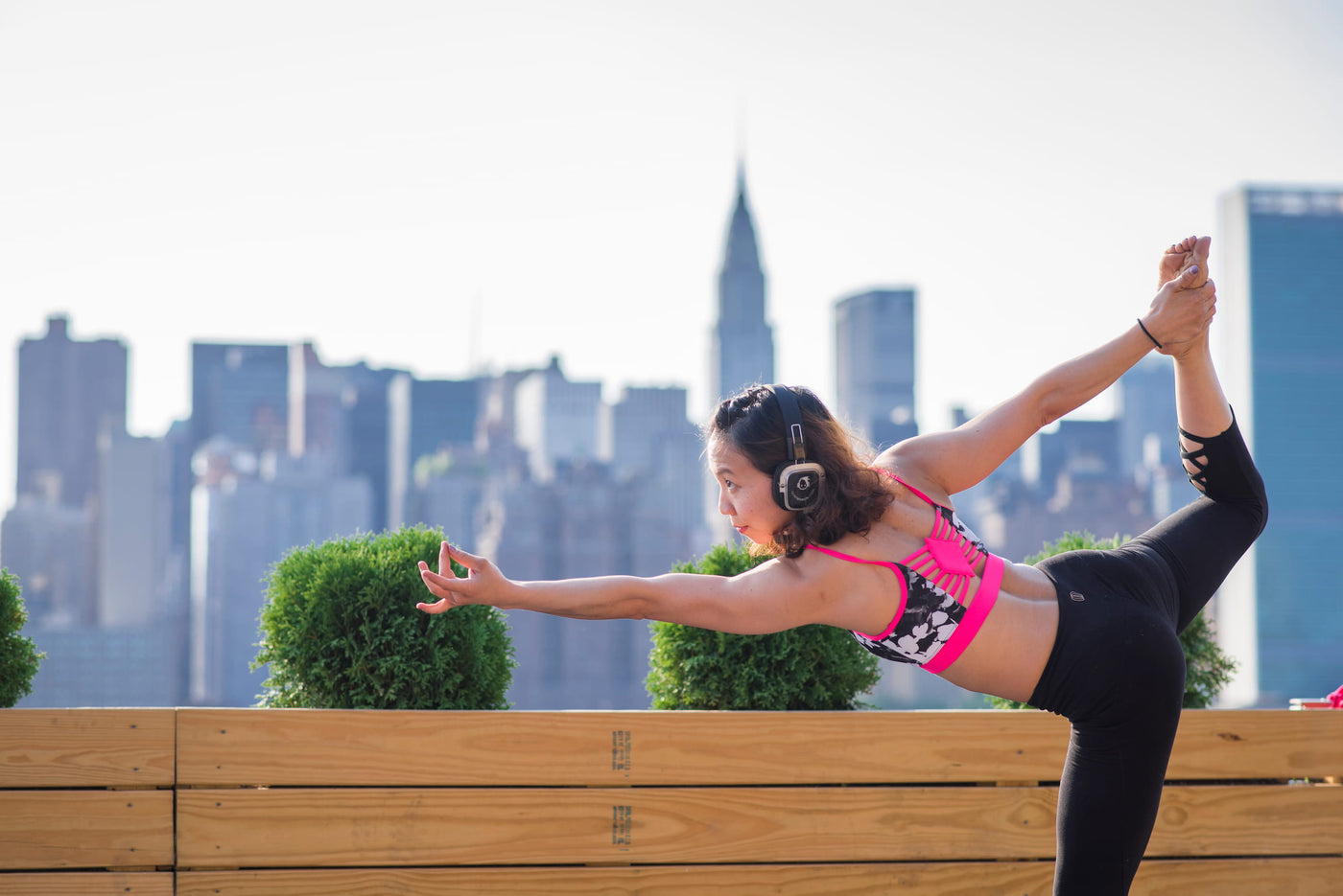 Quiet Events Silent Disco headphones for fitness and wellness.  A yoga student posing in a position outdoors wearing headphones.