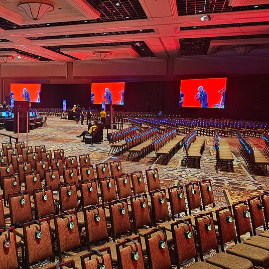 Quiet Events Silent Disco headphones for meetings a convention room filled with chairs and headphones  and screens.
