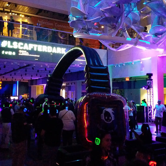 Quiet Events Silent Disco headphones for museums.  A group of people under a large headphone float having fun, dancing and enjoying their time.
