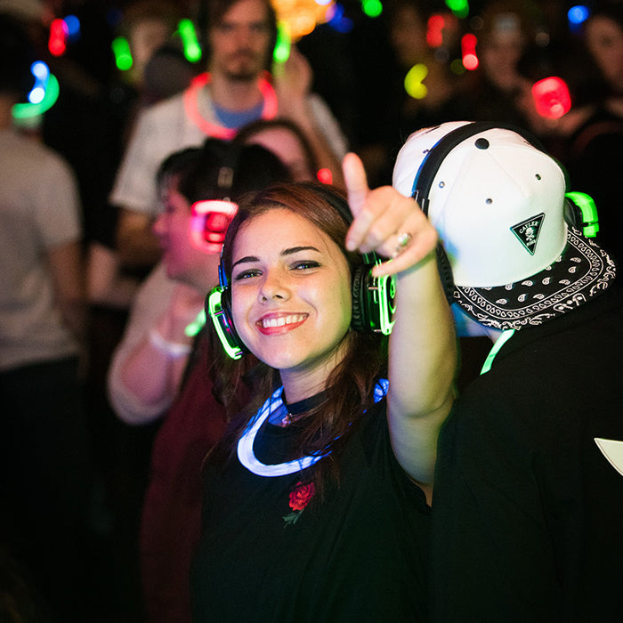 Quiet Events Silent Disco headphones for noise ordinances.  A girl posing and giving a thumbs up at a party with headphones.