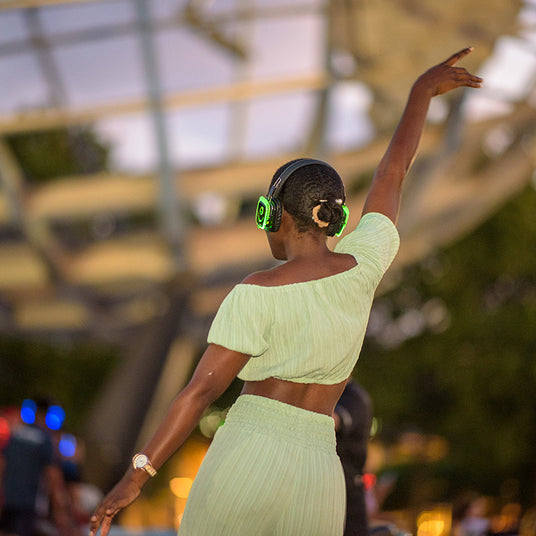 Quiet Events Silent Disco headphones for parks.  A black female with her back dancing with one of her hand in the air.