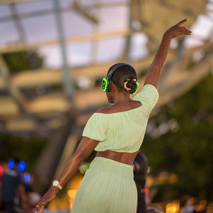 Quiet Events Silent Disco headphones for parks.  A black female with her back dancing with one of her hand in the air.