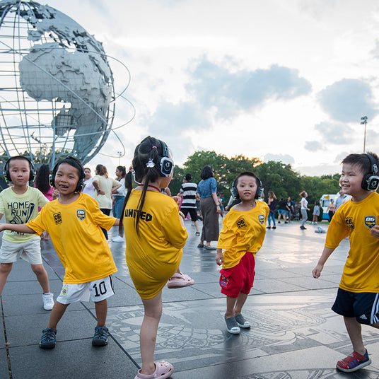 Quiet Events Silent Disco headphones for parks.  A group of children playing and dancing together wearing headphones.