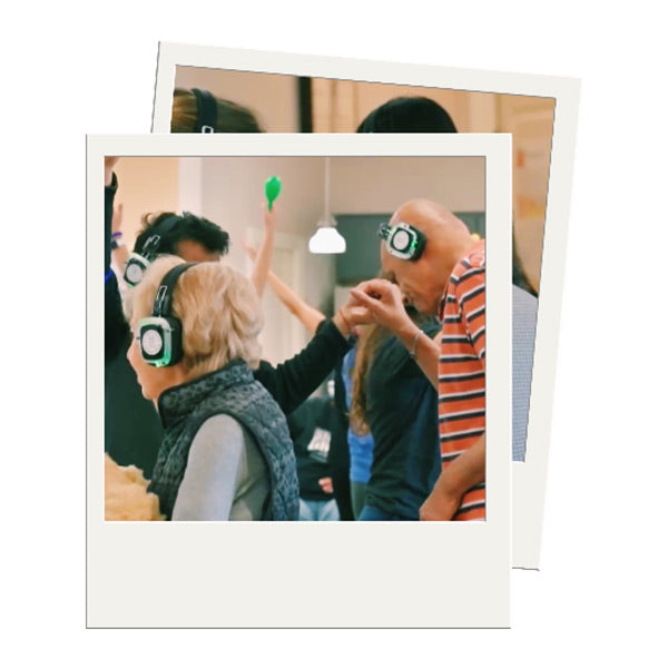 Quiet Events Silent Disco headphones for senior care.  Senior people standing dancing holding hands and wearing headphones.