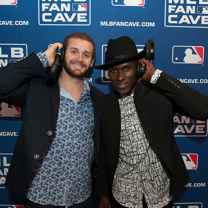Quiet Events Silent Disco headphones for sporting events.  two gentleman posing for a picture with headphones with a MLB background.