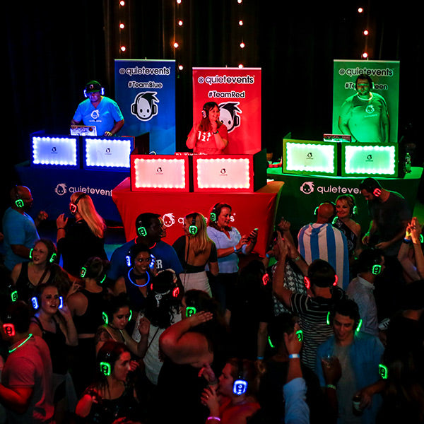Quiet Events Silent Disco headphones for dance parties a group of people dancing with headphones and three different DJ's in separate colors.