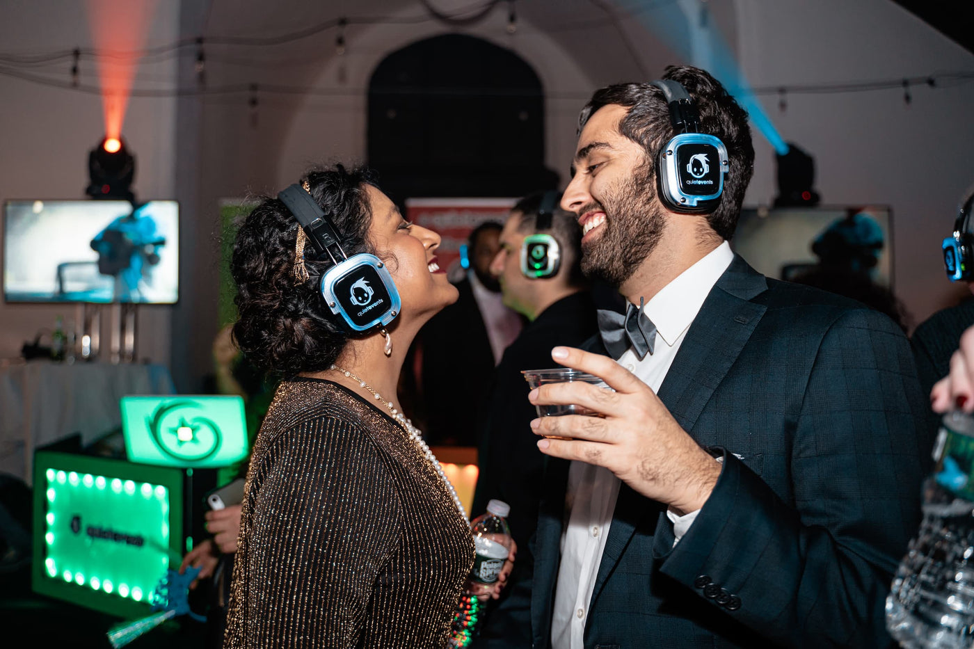 Quiet Events Silent Disco headphones for hotels.  A couple well dress happy and having fun with headphones.