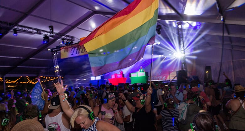 Guys waving the LGBTQ flag with headphones