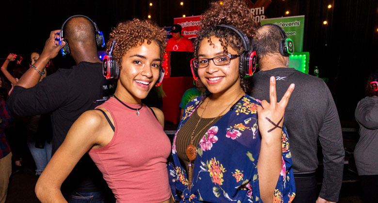 Two curly ladies wearing headphones enjoying the silent disco