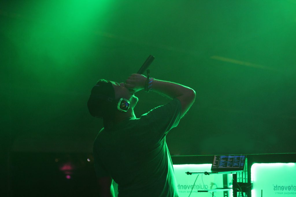 Green DJ holding the mic with headphones