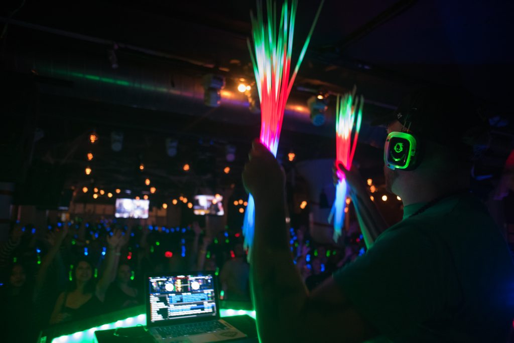 DJ holding neon stick with headphones