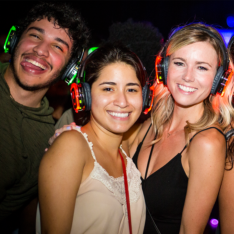 Three people wearing glowing headphones